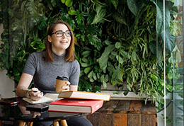 一位微笑著的年輕女子一邊喝咖啡一邊看書